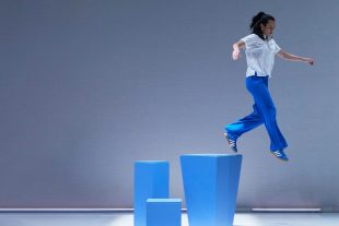 National Performing Arts Partnership Framework. Image is three blue blocks of varying heights with a performer dressed in blue trousers and white top seemingly stepping off one into thin air.