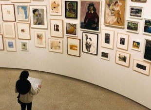 An art gallery wall covered with small paintings of all kinds. There are so many works it looks like an art prize exhibition.