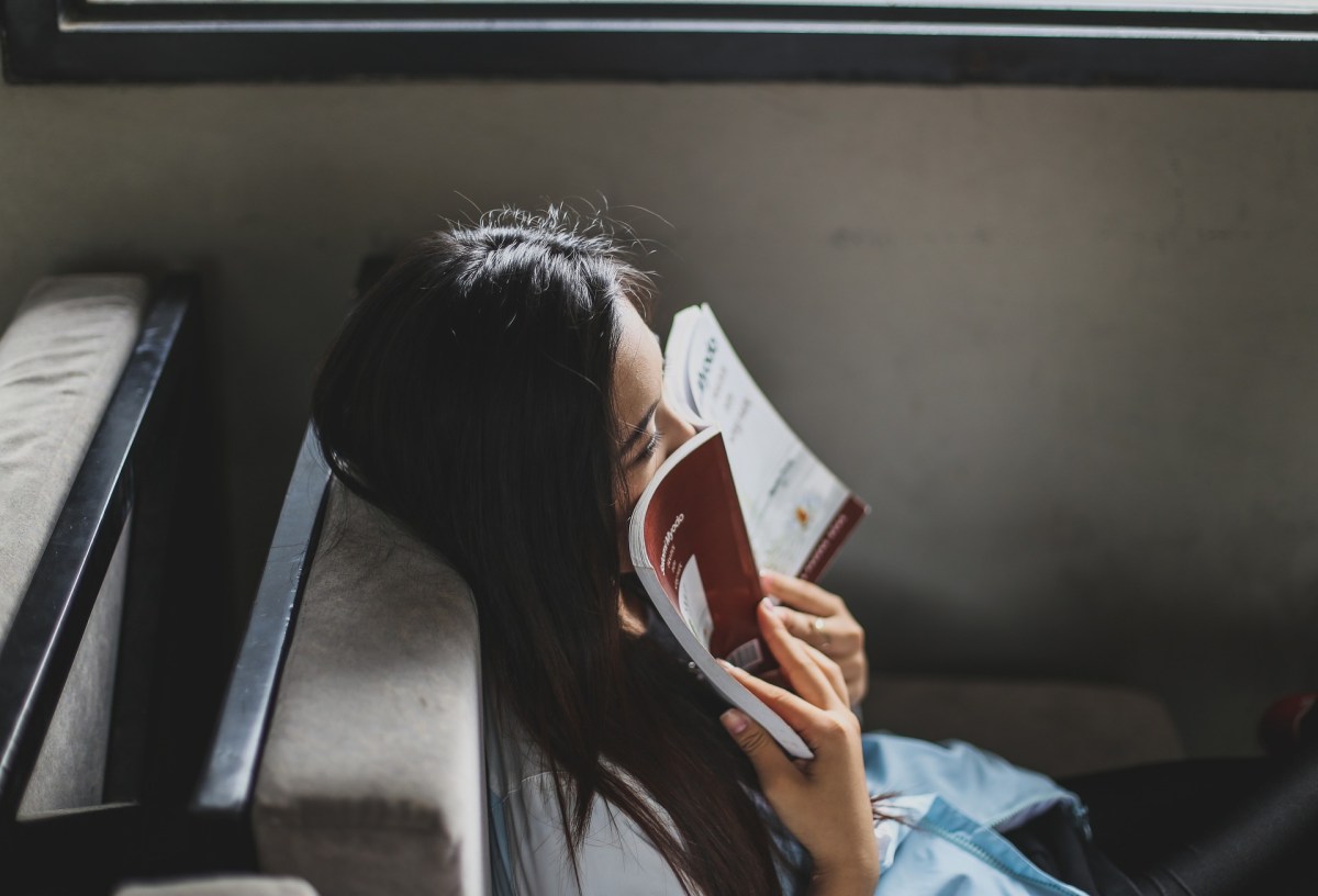 Stella Count. Profile of a woman with long black hair. She has a book pressed up against her nose.