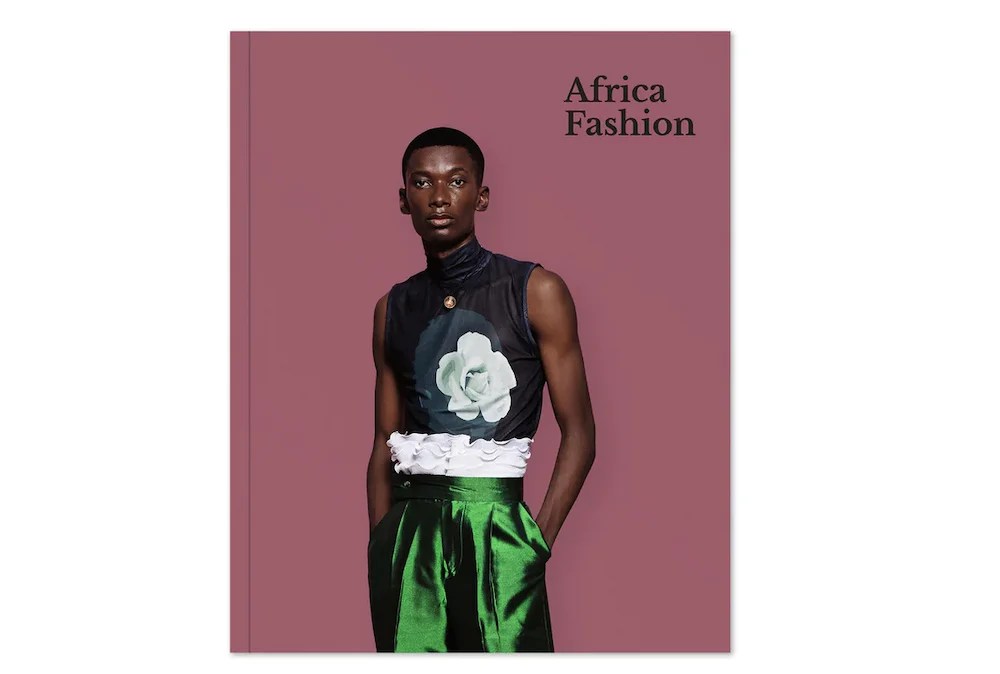 Pink book cover with African man wearing shiney green pants and top with flower.