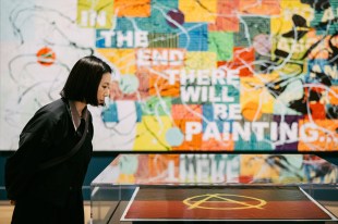 Young woman dressed in black looking at art in Aboriginal exhibition. First Nations.