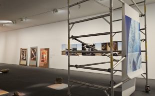 ‘Built Photography’ installation view at MAPh, featuring a print hanging from a scaffold on the right hand side, printed photographic images leaning against a wall and fabric printed pieces on the ground.