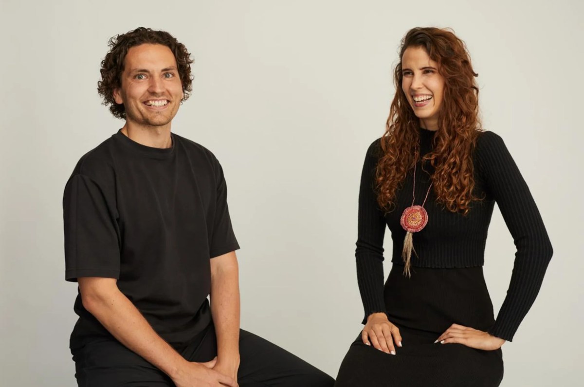 Young man and woman sitting on stools and laughing, wearing black.
