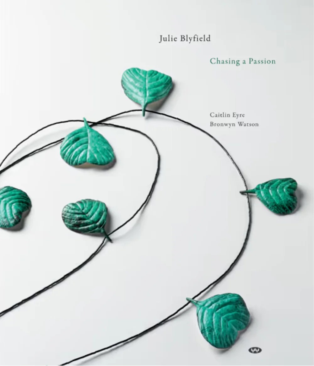White book cover with picture of necklace with green gems.