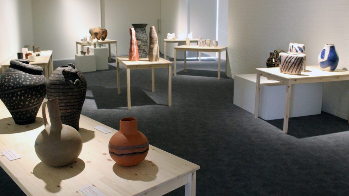 Various ceramic pots of different colours and shapes are sitting on tables.