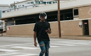 A geo-locator for live music gigs. Photo: Tnarg, Pexels. A person wearing headphones walking on the street with his phone out, seemingly in search of something.