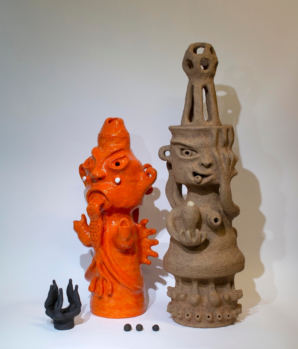 Clay handbuilt totemic figures in orange and brown colour. APT