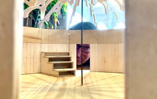 Peering inside the set design for the final Slingsby production, 'A Concise Compendium of Wonder'. In the photo, a man peers through a small doorway into the interior of the model.