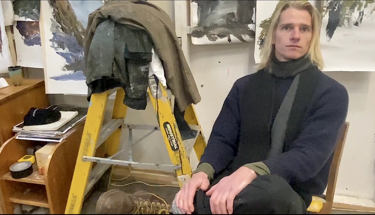 Man long blonde hair and navy jumper and scarf in painting studio. Harrison Bowe. Tasmania.