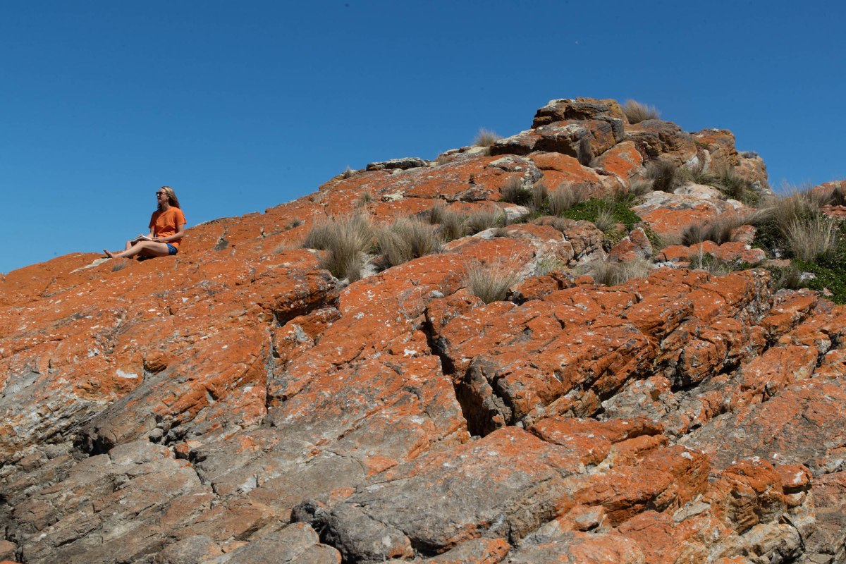 Girl drawing in outdoors sitting on red rocks. Zoe Grey.