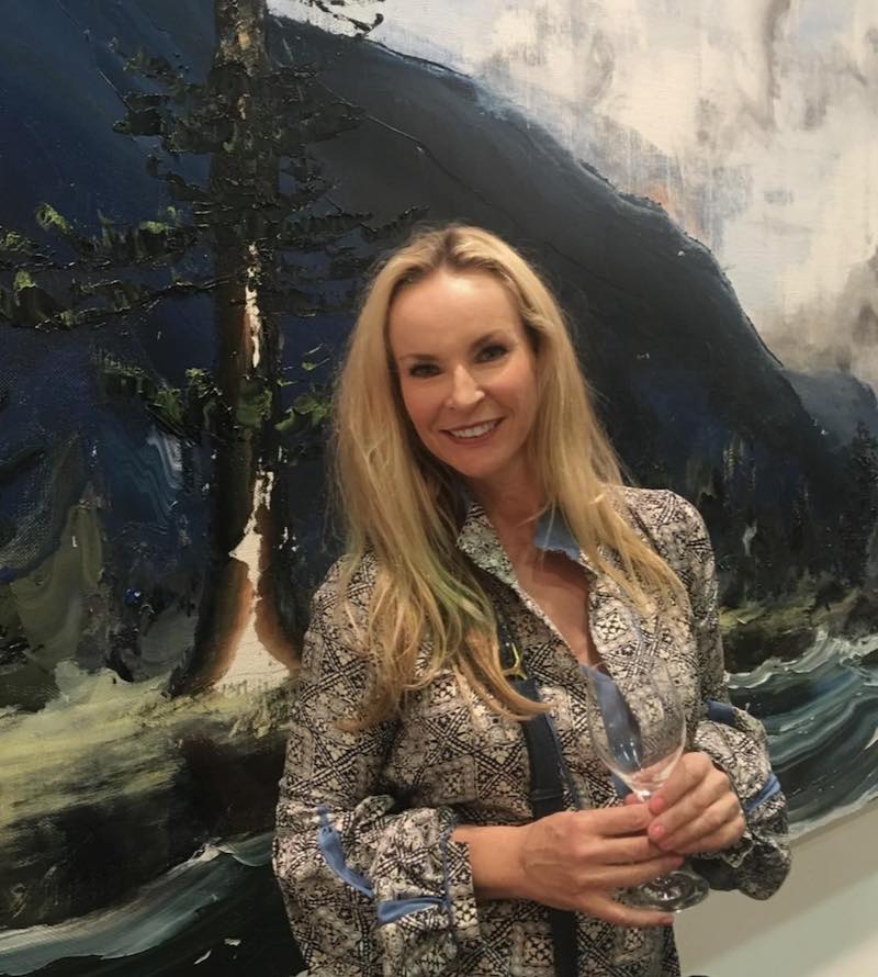 Woman with long blonde hair standing in front of a painting. Ask a curator