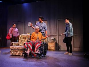 A woman and two man are standing around an elderly woman in a wheelchair in the production of 'Operation Boomerang.'