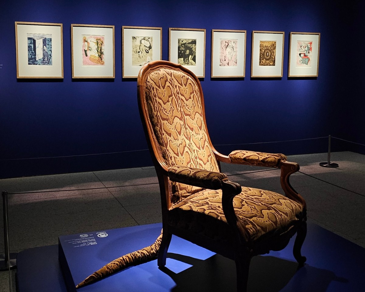 ‘Fantastic Visions: 100 Years of Surrealism from the National Galleries of Scotland’ at Museum of Art Pudong, Shanghai. A chair with snake print and a long tail displayed inside a gallery with ultramarine blue walls. Behind the chair is a selection of small artworks hung on the wall.