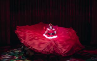 A woman wearing a Santa costume with enormous layers of skirt surrounding her.