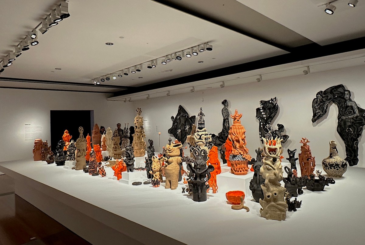 table with a collection of totemic clay sculptures in gallery setting. APT11