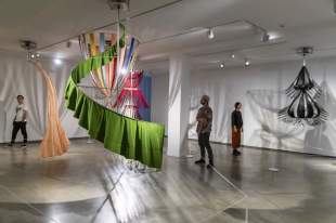 Museum of Contemporary Art: a picture of a colourful, free-hanging textile contemporary art installation in a large gallery space. Three people are in the gallery viewing the work.
