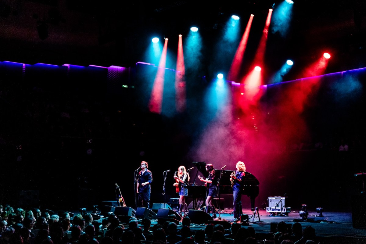 Three women and a man on stage with guitars. Rufus Wainwright Folk Bitch Trio.