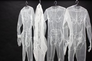 A group of transparent white body suits hang in front of a black backdrop, Dobell Prize.