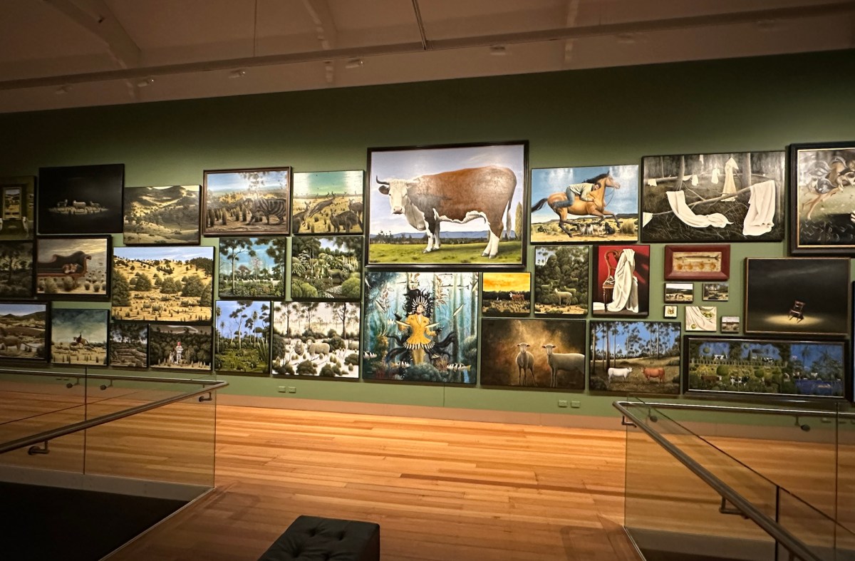 A gallery wall full of large paintings of the natural world.