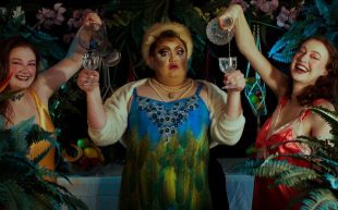 Promotional photo of a performance, where three performers appear to be having a drinking party, looking cheery in cocktail dresses.