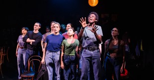 A group of young adults on stage. They are all dressed casually in jeans and t-shirts.