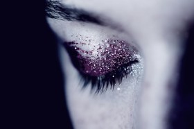 Black and white detail photo of woman's eye with glitter eye shadow. Arts news watch