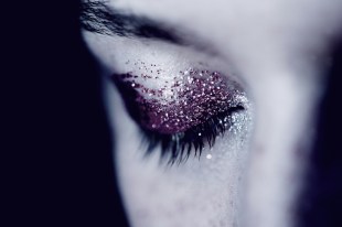 Black and white detail photo of woman's eye with glitter eye shadow. Arts news watch