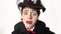 Close up of a young woman wearing black with a red bow tie and an elaborate bonnet.