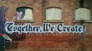 graffiti on building saying 'together we create'. Social cohesion.