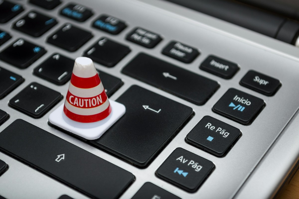 Image of laptop keyboard, with small warning traffic cone. Journalism