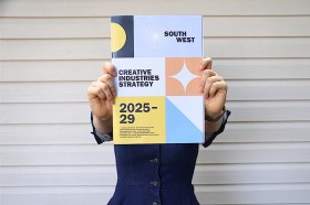 woman holding a strategic planning document in front of face. Arts planning