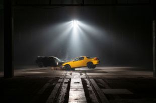 'Crash Body' by Paula Garcia, Dark Mofo 2025. Two cars, one yellow, one black, collide head-on under spotlights in a dramatic, moodily-lit photograph.