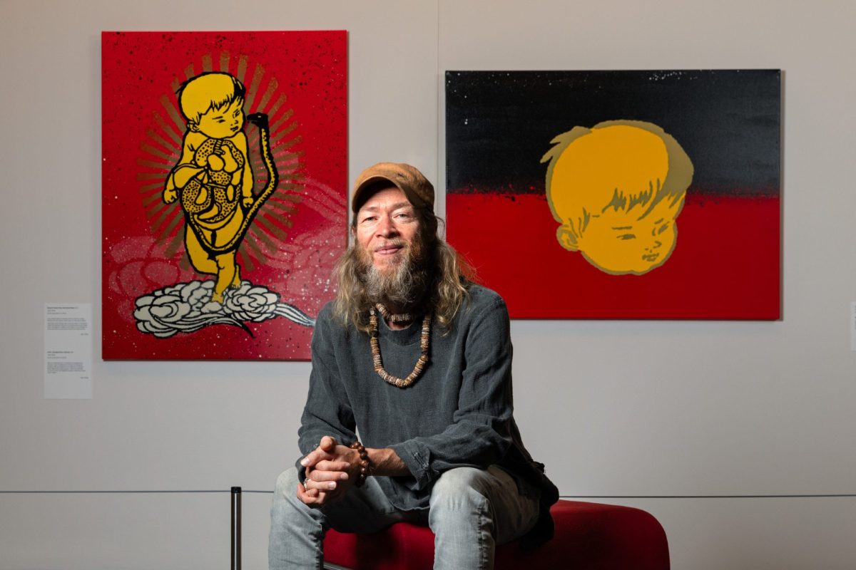 Artist Jason Wing pictured sitting in front of art works.