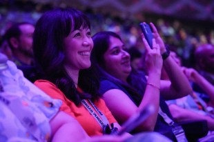 Smiling women seated in auditorium with purple lighting. SXSW