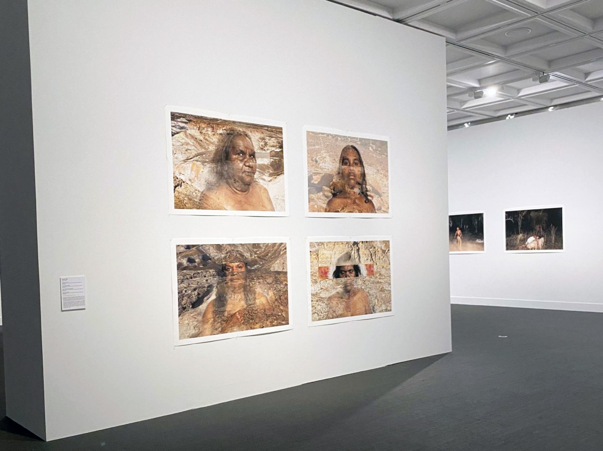 de-centre re-centre: installation view of a photographic exhibition in a gallery space. Four landscape orientation photographs of faces of Aboriginal women are placed on a wall in the foreground of this image.