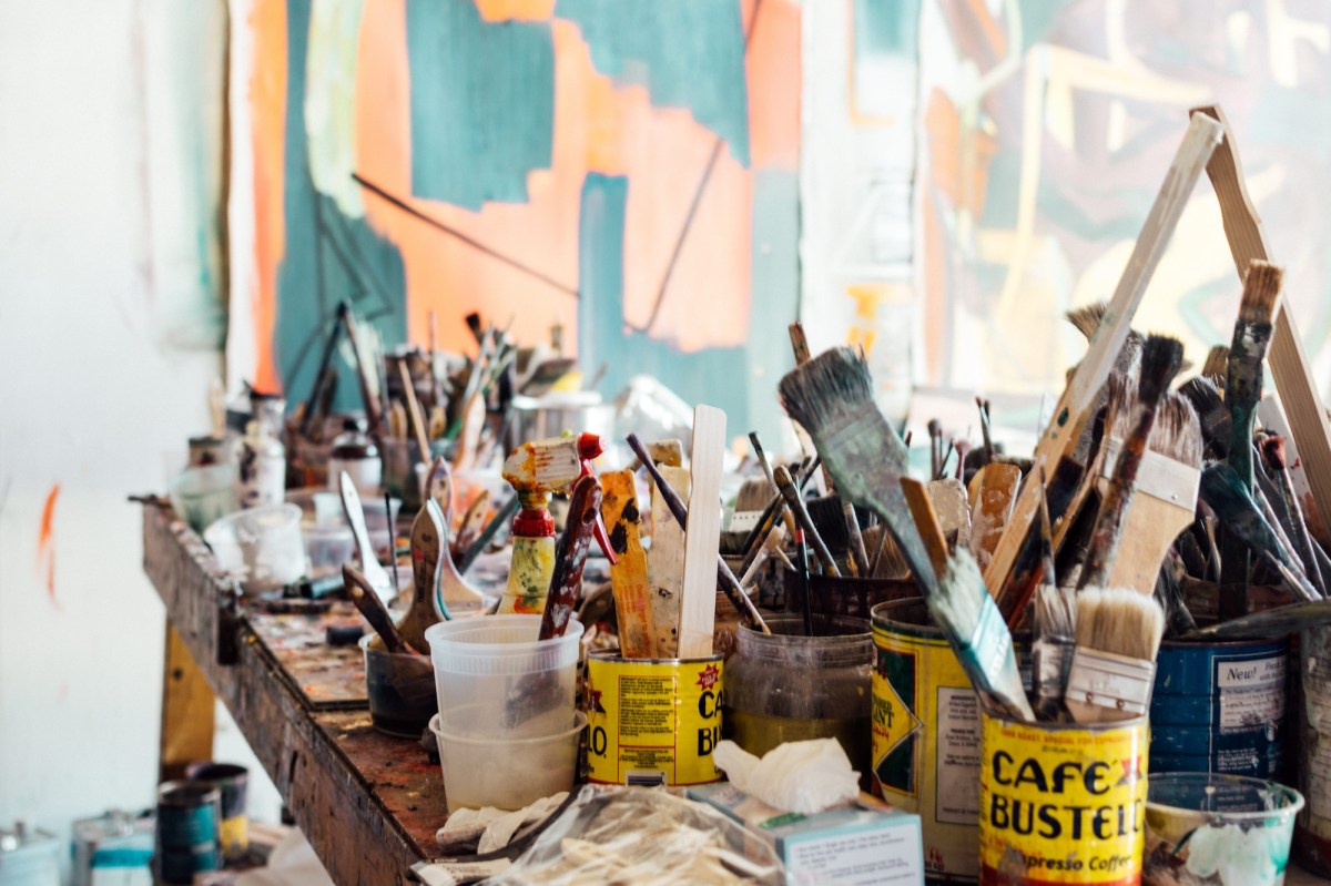 Artist table in studio covered with paintbrushes. Money tips for artists