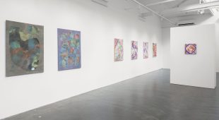 Abstract paintings hanging on a white wall.