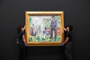 Two gallery assistants dressed in black hanging masterpiece painting in fold frame. Edvard Munch.