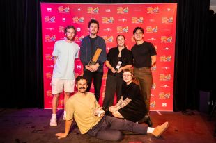 MICF 2025 award winners group photo; Garry Starr (aka clown Damien Warren-Smith) reclines at the front.