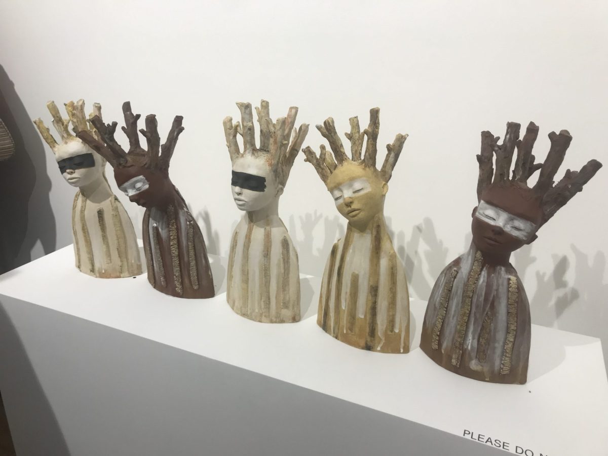 Five busts of humans heads with branch-offshoots growing out of them.