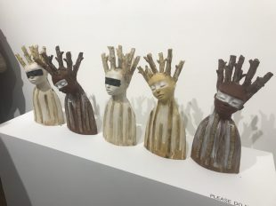 Five busts of humans heads with branch-offshoots growing out of them.