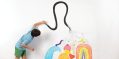 Child paints on white wall.