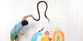 Child paints on white wall.