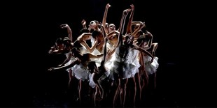 A group of ballerinas mid dance, dressed in white.