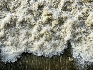 A close-up photo of waves crashing on a beach, illustrating ArtsHub's weekly On the move column, a wrap-up of arts sector appointments and departures.