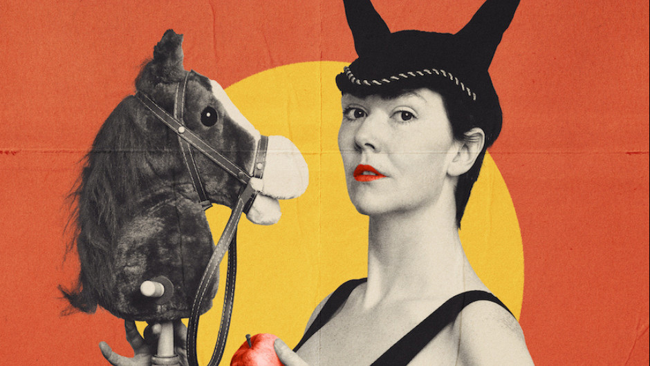 Against a yellow and orange backdrop a woman is carrying a hobby horse. She is also wearing horses ears hat.