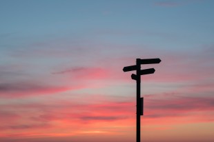 Pink and blue soft sky with silhouette of sign post. Arts policy.