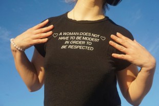 women in black t-shirt with feminist slogan against blue sky