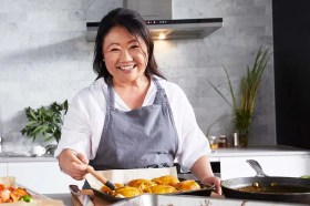 Nagi, a middle-aged Japanese-Australian woman with black hair, in a kitchen cooking and smiling at the camera. She is making plagiarism claims against another cookbook author.