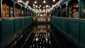A group of spectators surround a body of water in an immersive theatre experience by Phatom Peak.